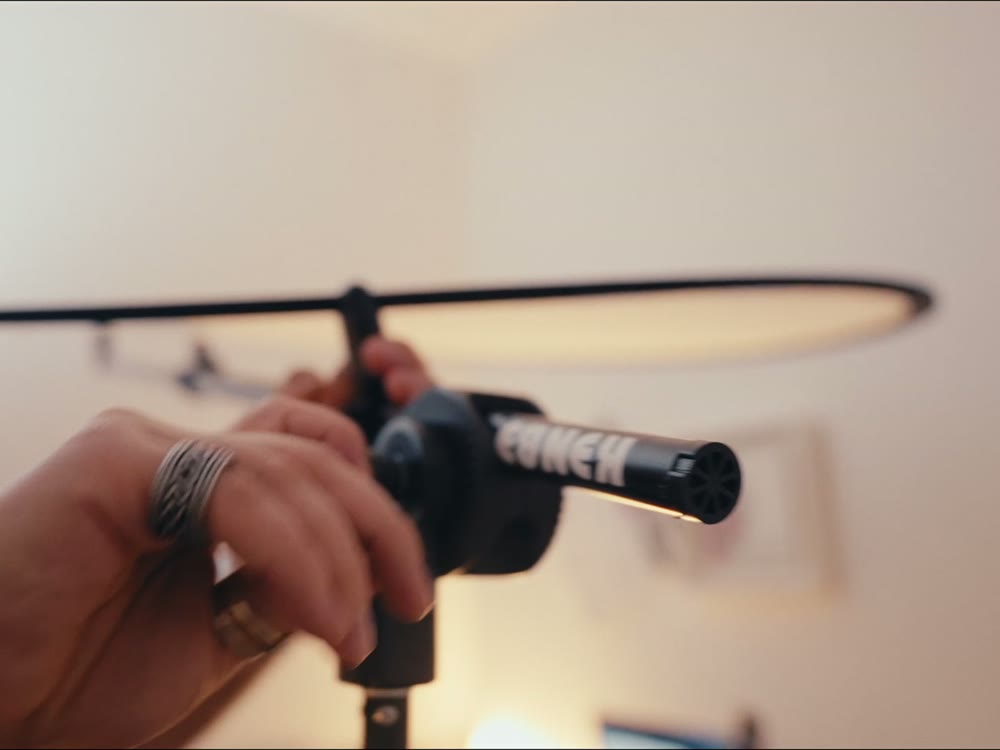 A hand tightening a boom arm that holds a reflector
