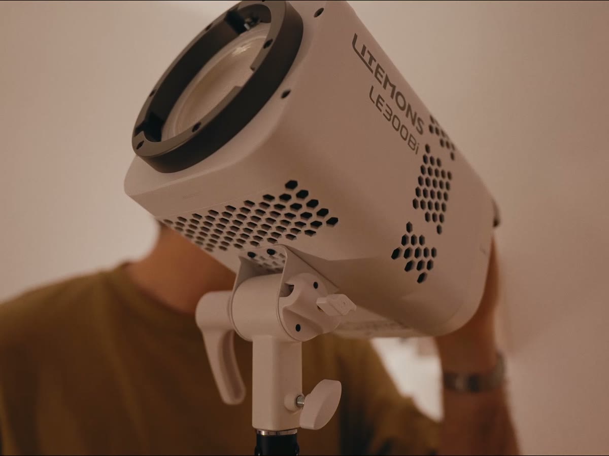 A hand securing a studio light on its stand