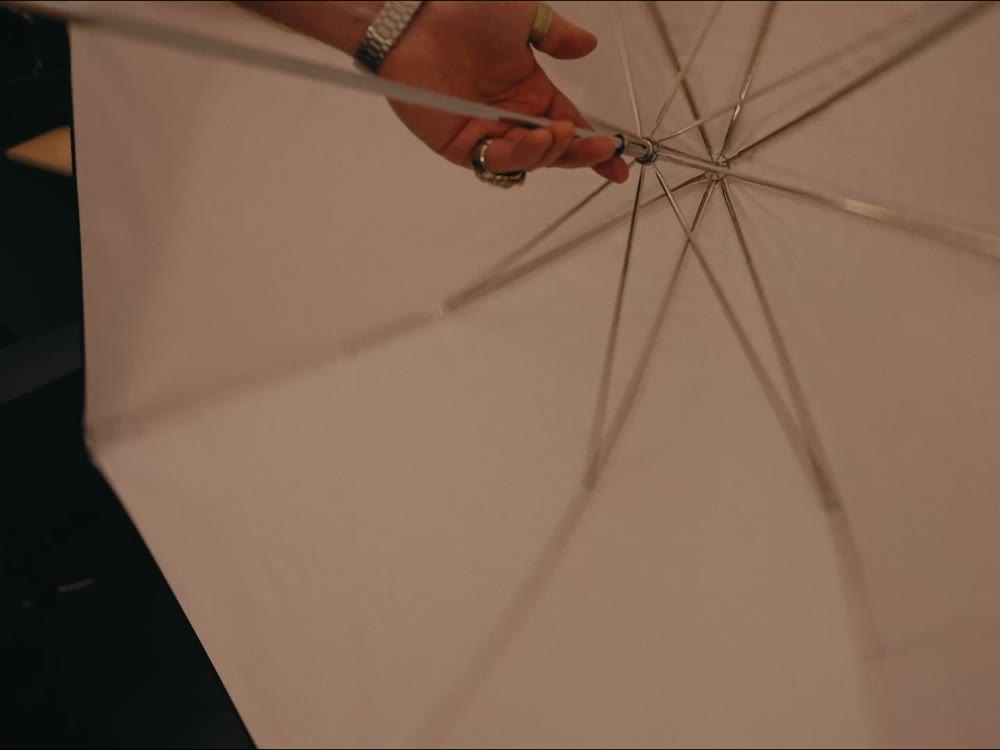 A hand opening a white studio umbrella